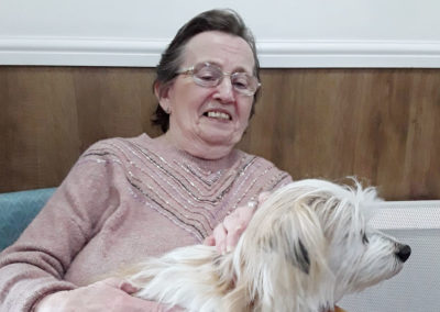Resident at Sonya Lodge smiling with a dog on her lap