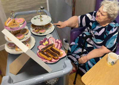 Sonya Lodge Residential Care Home resident enjoying choosing a cake from an Alice in Wonderland afternoon tea trolley