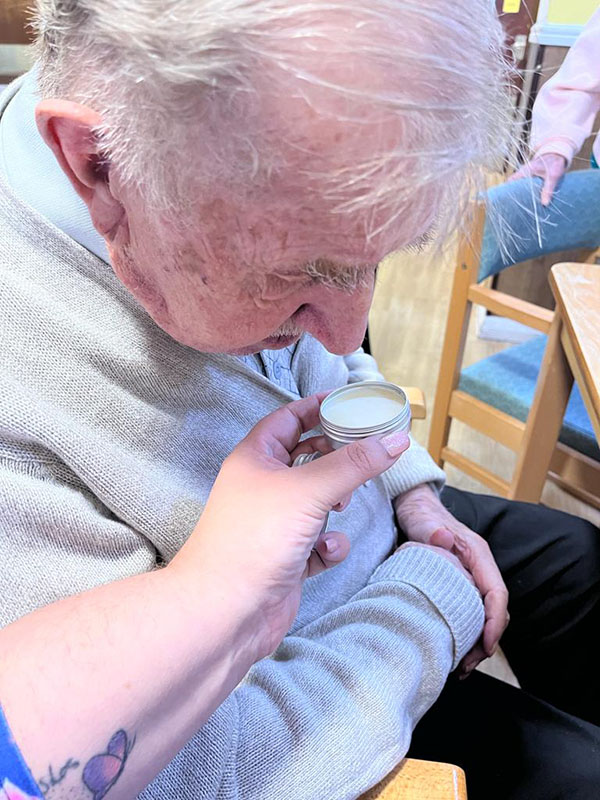 Sonya Lodge Residential Care Home resident smelling a scent in a pot 