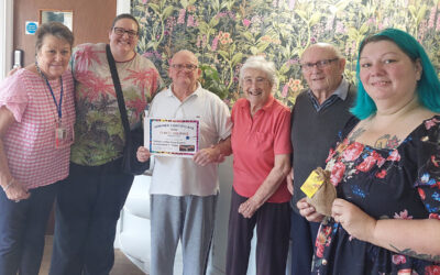 Residents and team members at Sonya Lodge Care Home smiling together while proudly holding their Crafty Creature competition winner’s certificate.