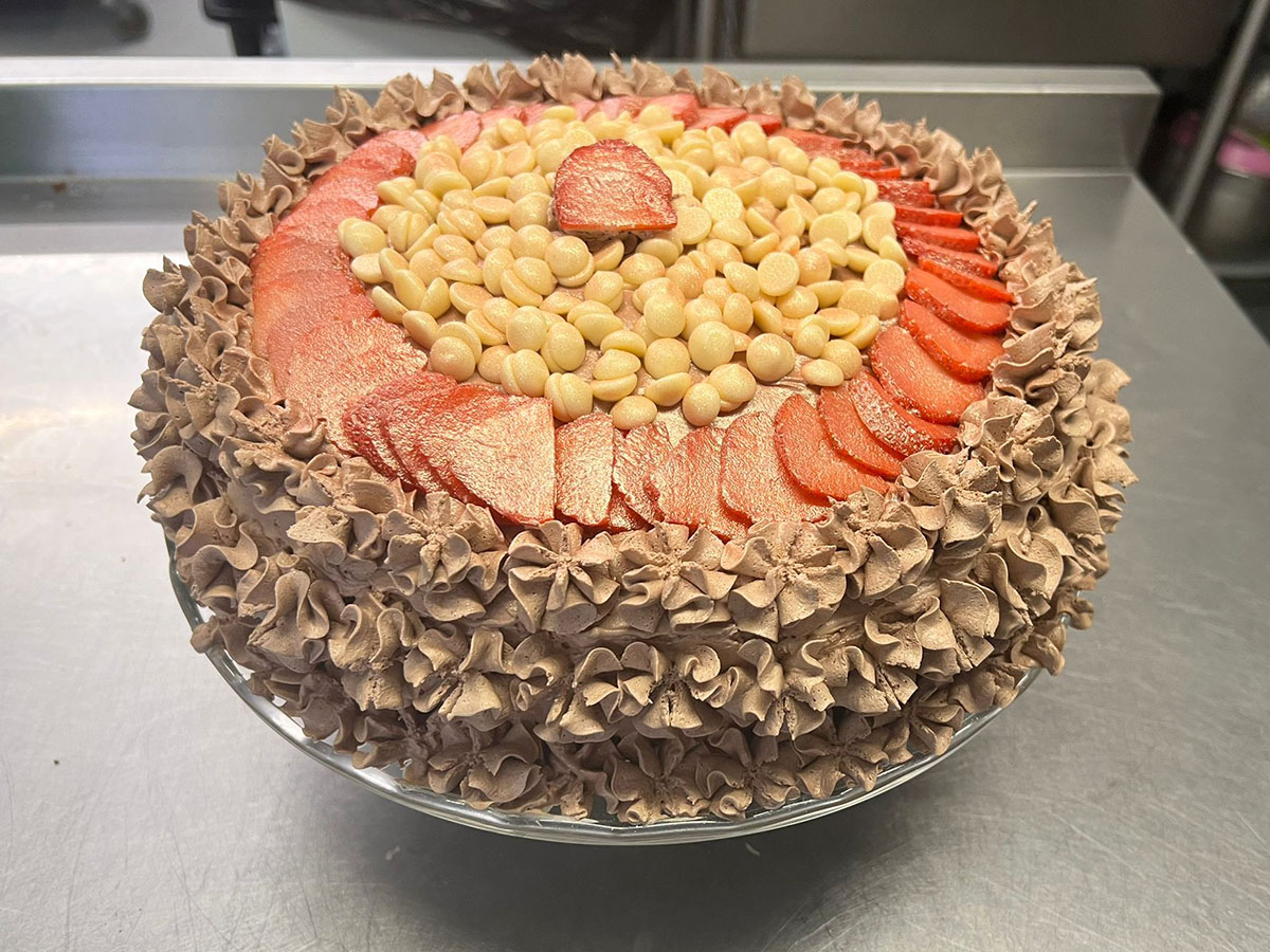 Delicious resident birthday cake covered with chocolate piping, chocolate drops and fresh sliced strawberries at Sonya Lodge Residential Care Home.