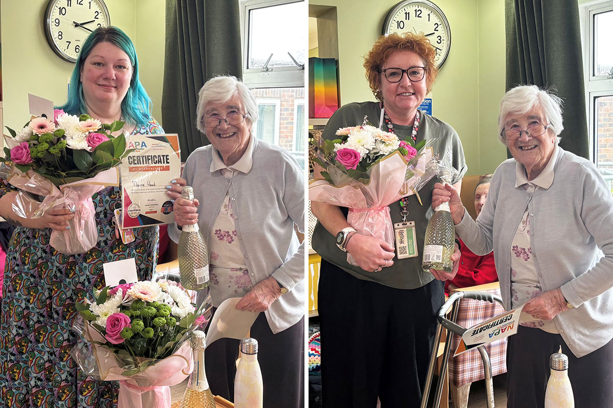 Recreation and Well-being Team members receiving gifts and flowers with a resident as part of National Activity Providers and Professionals Week at Sonya Lodge.